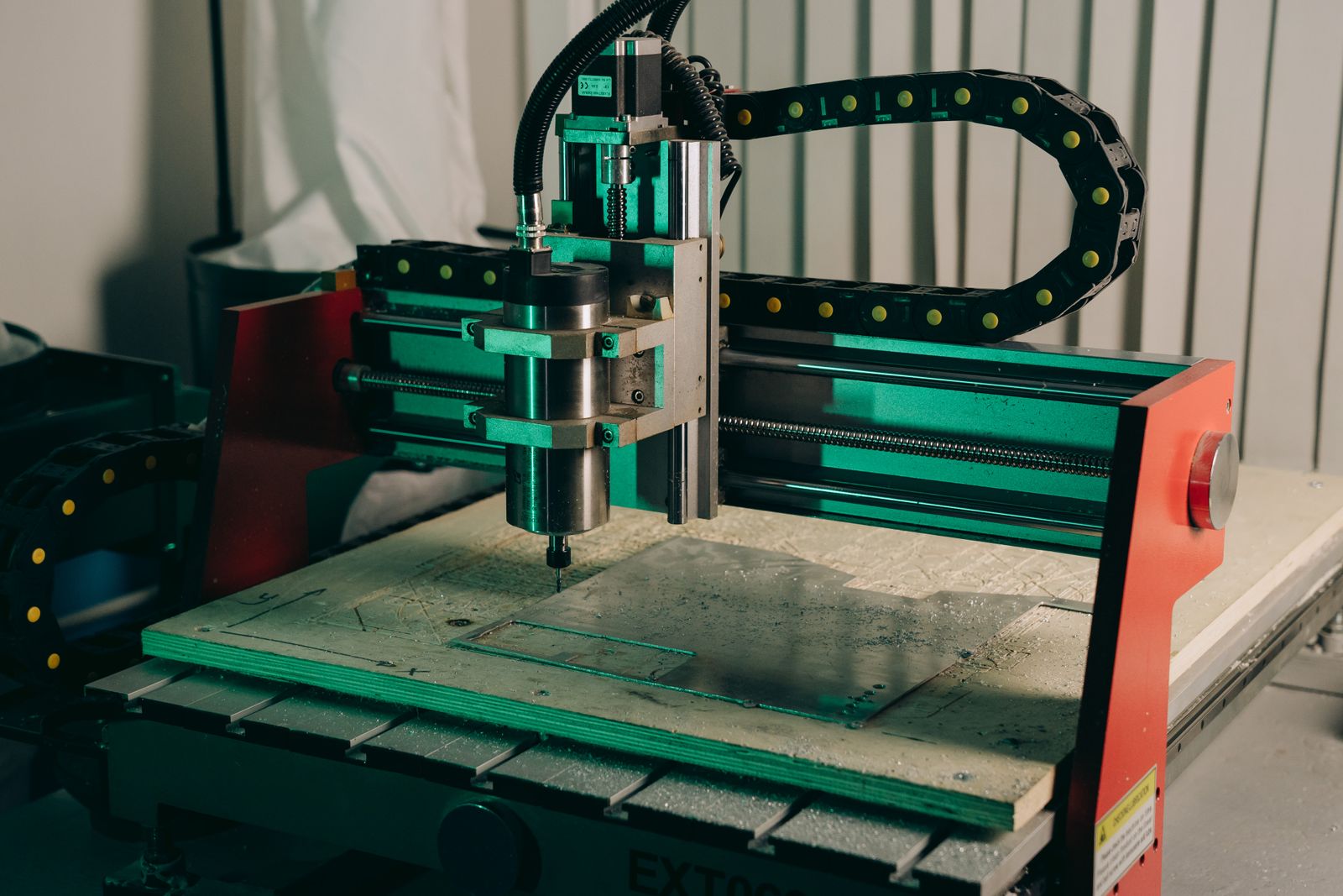 Operator CNC kontrolujący pracę obrabiarki i wymiary metalowego detalu.